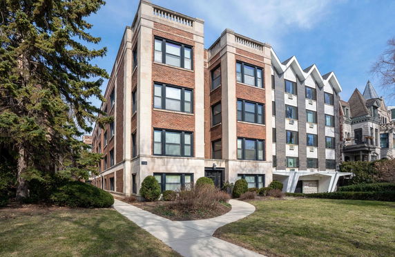 Front view of a multi-story apartment building with brick and stone facade.