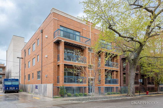 Front view of a three-story brick building with balconies.