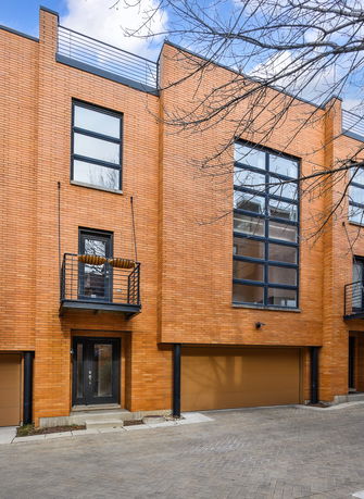Front view of a modern brick house with large windows and a small balcony.