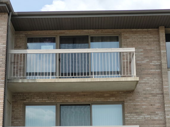 Front view of a building with a balcony and sliding glass doors.