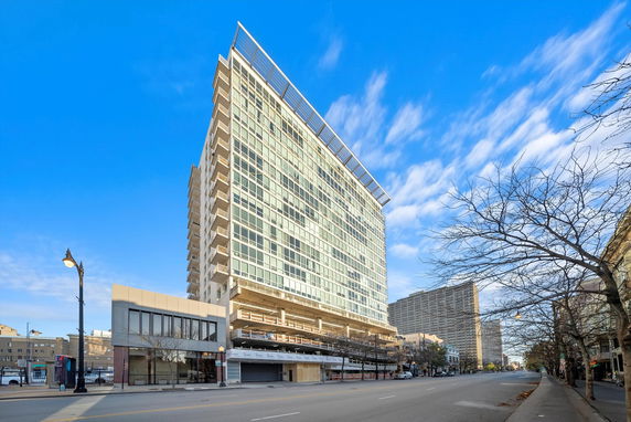 Front view of a tall, modern apartment building with many windows and a grid-like facade.
