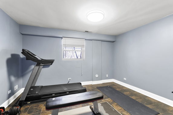 Interior room with exercise equipment including a treadmill and bench.