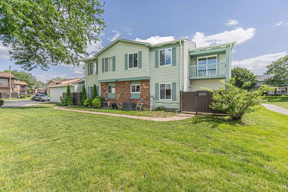 Front view of a two-story house with a mix of brick and light green siding.