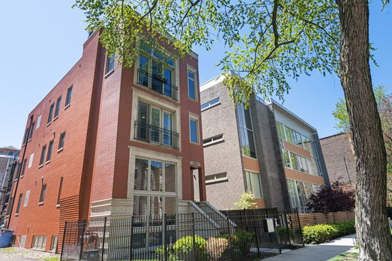 Front view of a modern multi-story residential building with a brick facade and large windows.