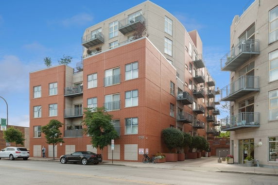 Front view of a multi-story apartment building with brick facade and balconies.
