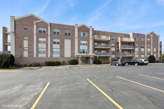 Front view of a multi-story residential building with parking area.