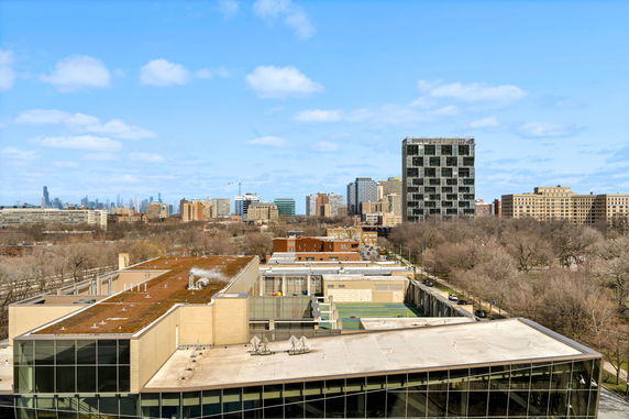 Panoramic view of a cityscape with multiple buildings, including a tall, modern structure in the foreground.