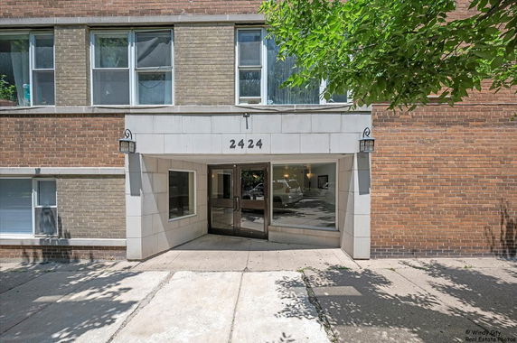 Front view of a brick building with large entrance and glass doors.
