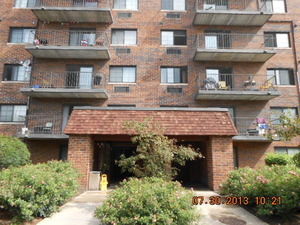 Front view of a multi-story brick apartment building with balconies.