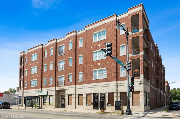 Front view of a multi-story brick apartment building on a street corner.