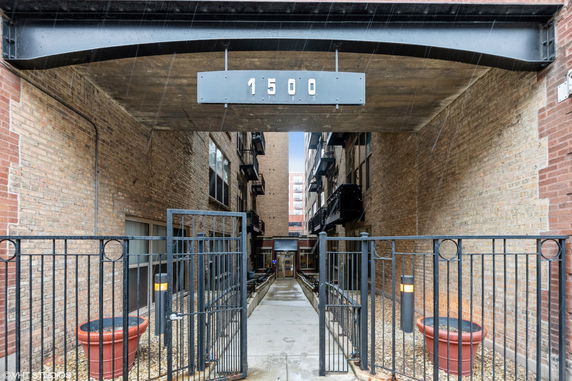 Entrance view of a multi-story brick building with an overhead address sign.