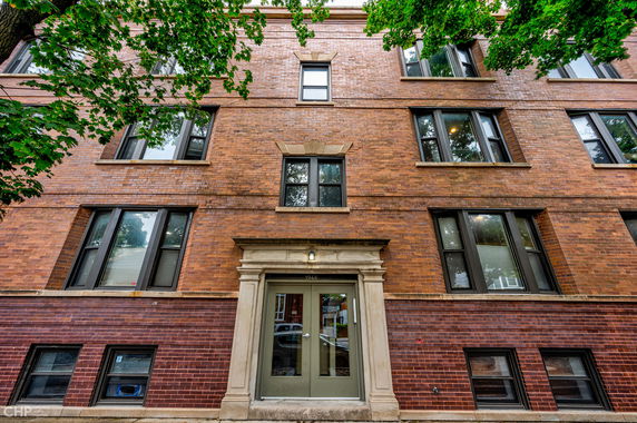 Front view of a brick apartment building with multiple windows and a central entrance.