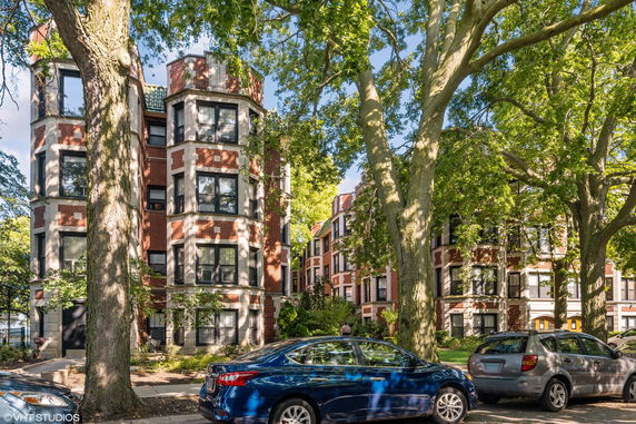 Front view of multi-story brick building with large windows and surrounding trees.
