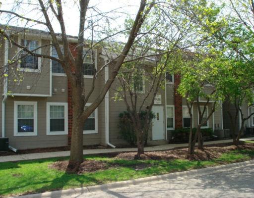 Front view of a two-story apartment building with a simple facade and surrounding trees.