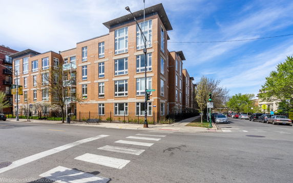 Front view of a multi-story brick apartment building with large windows.
