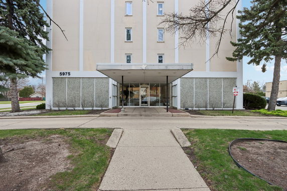 Front view of a multi-story building with a covered entrance and large windows.