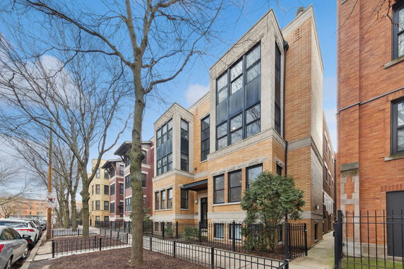 Front view of a modern multi-story building with large windows and brick facade.