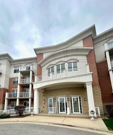 Front view of a multi-story building with balconies and a covered entrance.