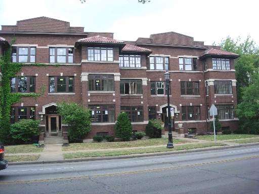 Front view of a three-story brick building with multiple windows.