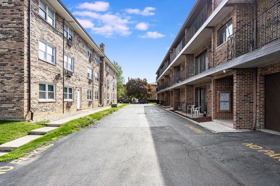 Exterior view of two adjacent brick apartment buildings with multiple floors and balconies.