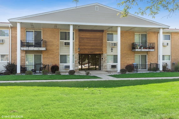 Front view of a two-story apartment building with balconies and large columns.