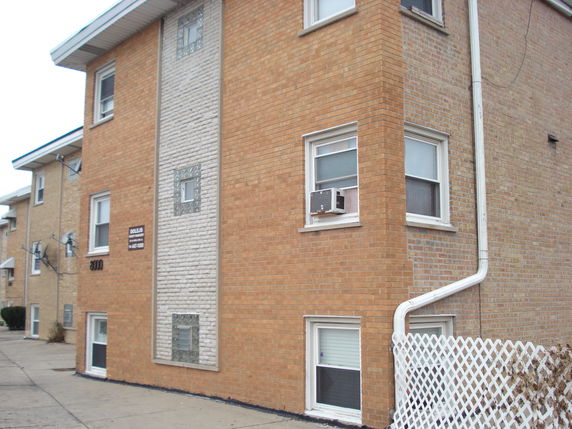 Front view of a multi-story brick building with rectangular windows and air conditioning units.