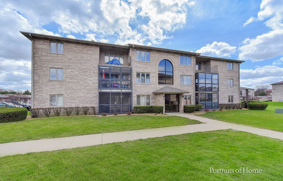 Front view of a three-story apartment building with large windows and a central entrance.