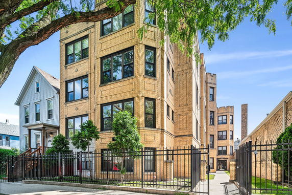 Front view of a multi-story brick apartment building with large windows.
