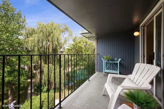 Balcony view overlooking lush green trees with outdoor seating.
