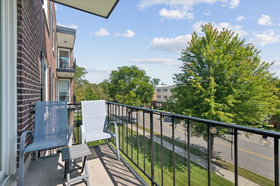 View from a building balcony showing surrounding street and trees.