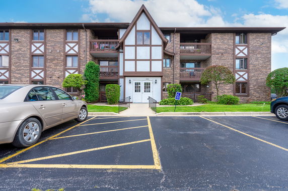 Front view of a multi-story building with a brick facade and wooden balconies.
