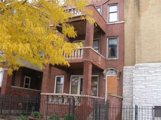 Front view of a multi-story brick building with a covered porch and balcony.
