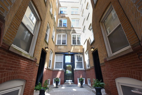 View of a multi-story brick building entrance with multiple windows.