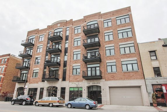 Front view of a multi-story brick building with balconies and large windows.