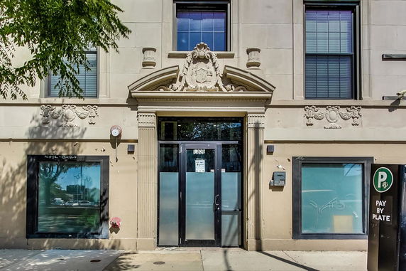 Front view of a building entrance with decorative stonework and large windows.