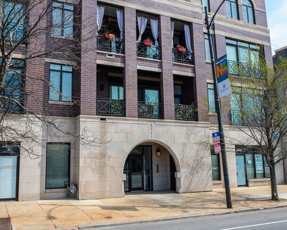 Front view of a multi-story brick building with balconies and arched entrance.