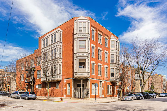 Front view of a multi-story red brick building with decorative white window frames on a corner lot.