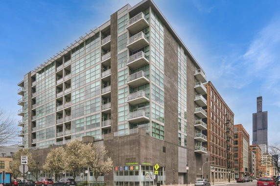 Front view of a modern multi-story building with glass balconies.