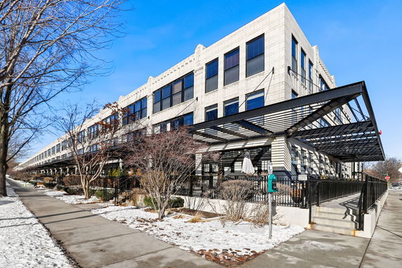 Side view of a large multi-story building with large windows and a metal canopy.