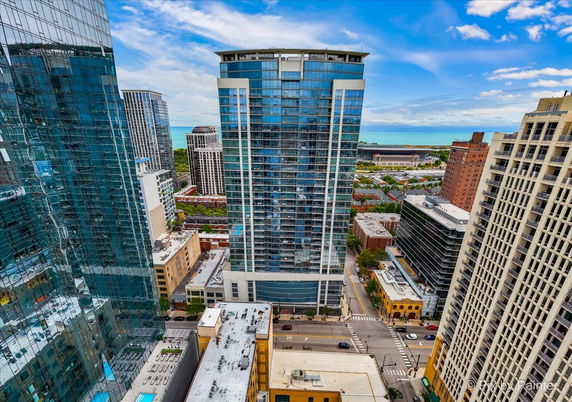 View of multiple high-rise buildings in an urban setting with a glimpse of a body of water in the background.