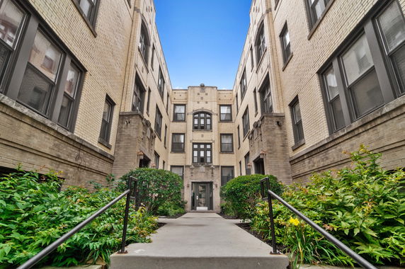 Front view of a multi-story brick apartment building with multiple windows.