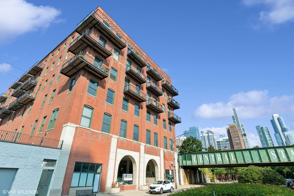 Front view of a multi-story brick building with balconies and arched entrances.