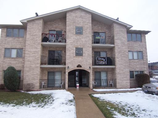 Front view of a multi-story brick apartment building with balconies.