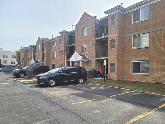 Front view of a multi-story residential building with brick exterior and balconies.