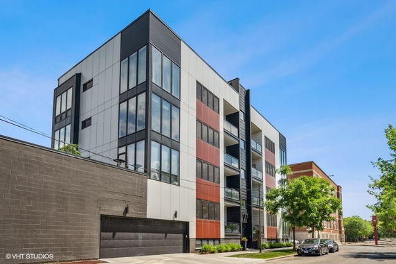 Front view of a modern multi-story apartment building with large windows and balconies.