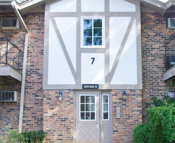 Front view of a brick building with decorative wood trim and a central door.