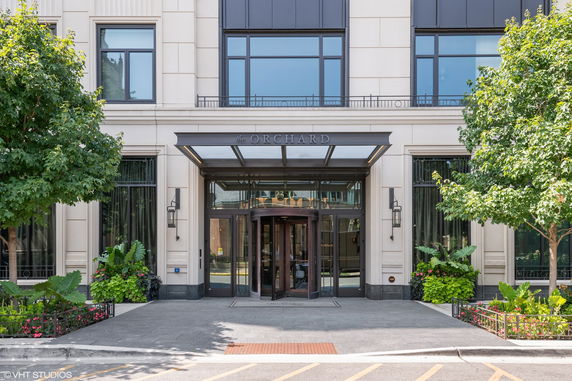 Front view of a building entrance with glass canopy and trees.