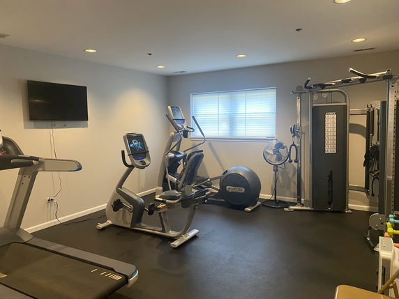 Indoor gym area with exercise equipment and a television.
