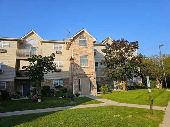Front view of a three-story brick and siding apartment building.