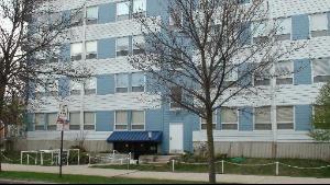 Front view of a multi-story apartment building with blue and white exterior.